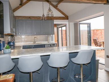 A kitchen with blue cabinets white marble countertop four chairs and glass pendant lights at Owl View Lebberston near Cayton