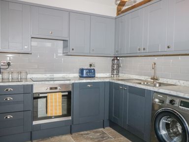A kitchen with blue cabinets a stainless steel oven a blue toaster and a washing machine at Owl View in Lebberston near Cayton