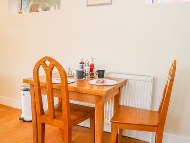 A dining area with a wooden table and two wooden chairs with cups and condiments on the table at Harbour View Mudeford Christchurch