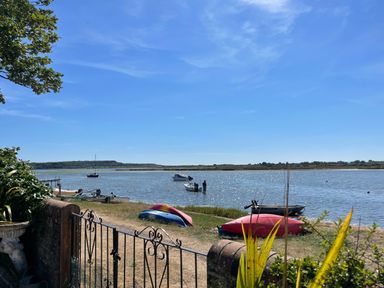 A waterfront with small boats and kayaks near a metal gate at Harbour View Mudeford in Christchurch