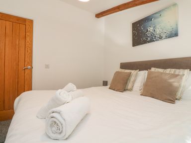 A bedroom with a bed set with pillows and rolled white towels on the bed at Sea Breeze 17 Gannel in Porthtowan