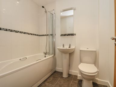 A bathroom with a bathtub shower sink mirror and toilet at Sea Breeze 17 Gannel in Porthtowan