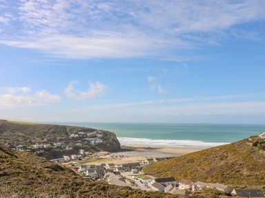 A coastal village with houses between hills and a sandy beach by the sea at Sea Breeze 17 Gannel in Porthtowan