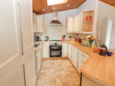 A kitchen with white cabinets wooden countertops a stove flowers and breakfast items on the counter at Fell View Lodge in Troutbeck