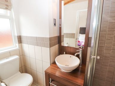 A bathroom with a toilet sink with a wooden vanity and a mirror at Fell View Lodge in Troutbeck