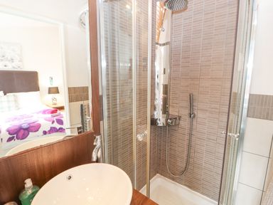 A bathroom with a glass shower enclosure and a sink basin seen next to a bedroom at Fell View Lodge in Troutbeck