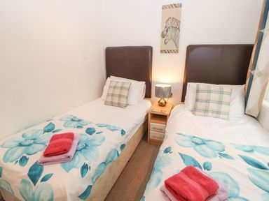A bedroom with two single beds each with floral blankets and plaid pillows at Fell View Lodge in Troutbeck