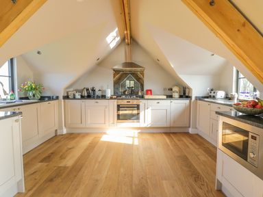 A kitchen with wooden floors appliances and kitchen counters at The Coach House in St Columb Major