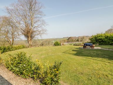 A large garden with a tree and a covered picnic table at The Coach House in St Columb Major