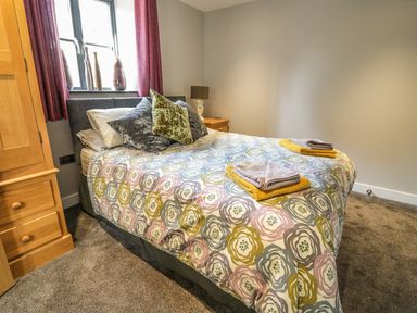 A bedroom with a bed covered in patterned bedding and folded towels at The Coach House in St Columb Major