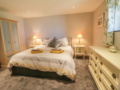 A bedroom with a bed lamps bedside tables wardrobe and a dresser at The Coach House in St Columb Major