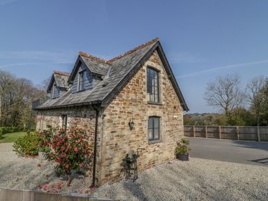 A stone house with two dormer windows and a gravel driveway at The Coach House in St Columb Major