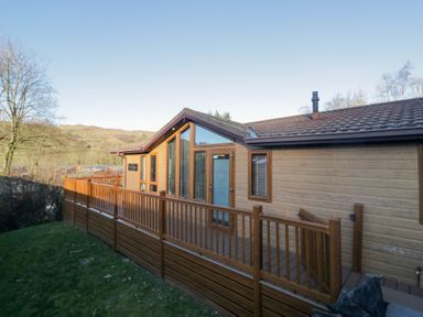 A cabin exterior with a wooden deck and large windows at Heights View