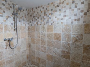 A tiled shower area with a wall-mounted showerhead at The Lookout -The House With A View in Weymouth