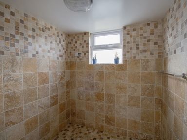 A tiled shower area with a small window and two potted plants at The Lookout The House With A View in Weymouth