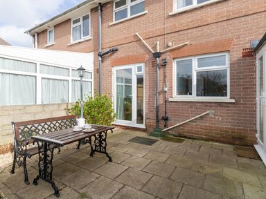 An outdoor patio area with a wooden table and bench a lamp post and a brick wall at The Lookout -The House With A View in Weymouth