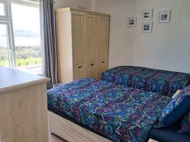 A bedroom with two beds and a wardrobe at The Lookout -The House With A View in Weymouth