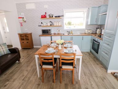 A kitchen with a dining table set for four and light blue cabinets at Dairy Cottage Tavernspite near Narberth