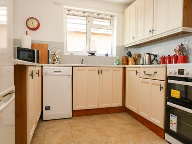 A kitchen with cabinets dishwasher microwave stove kettle and utensils at Dartmoor 2 in Callington