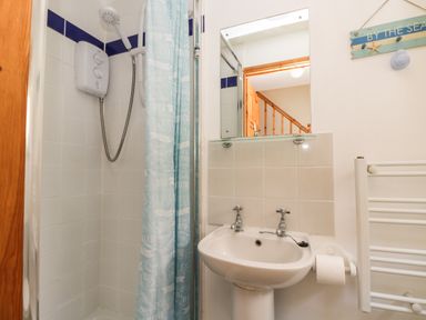A bathroom with a shower area and a sink with taps and a mirror above at Dartmoor 2 in Callington