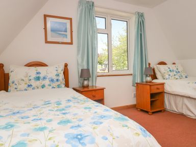 A bedroom with two single beds a window with curtains and two bedside tables with lamps at Dartmoor 2 in Callington