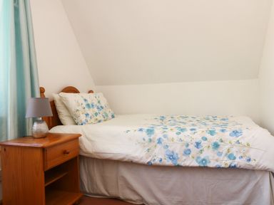A small bedroom with a wooden bed with floral bedding and a wooden bedside table with a lamp at Dartmoor 2 Callington