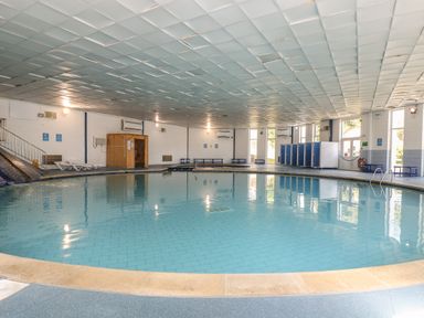 An indoor swimming pool with lockers benches and a wooden sauna at Dartmoor 2 in Callington