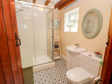 A bathroom with a shower enclosure sink toilet mirror and window at Isaacs Cottage in Spartylea near Allendale