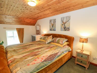 A bedroom with a double bed bedside table lamp and two paintings on the wall at Isaacs Cottage Spartylea near Allendale