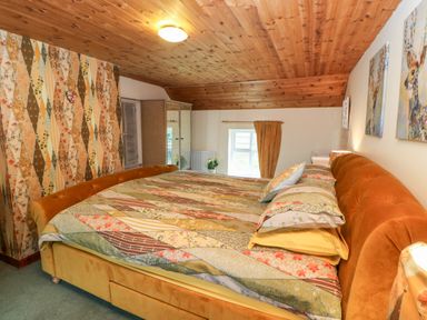 A bedroom with a bed covered in a patchwork quilt under a wooden ceiling at Isaacs Cottage in Spartylea near Allendale