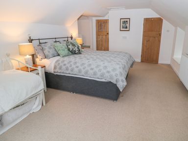 A bedroom with a double bed and a single bed with lamps on bedside tables at West Burnbank in Tarset near Bellingham