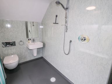 A bathroom with a wall-mounted toilet sink mirror and a walk-in shower at West Burnbank in Tarset near Bellingham