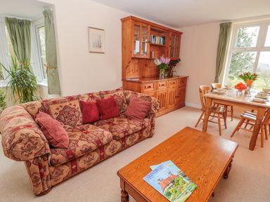 A living room with a patterned sofa wooden coffee table and dining table with chairs at West Burnbank in Tarset near Bellingham