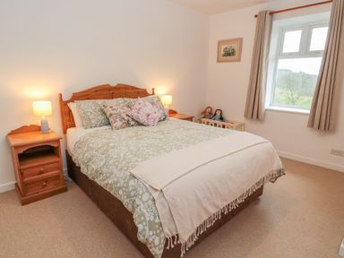 A bedroom with a wooden bed and matching bedside tables with lamps at West Burnbank in Tarset near Bellingham