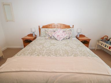 A bedroom with a double bed nightstands with lamps a small mirror on the wall and a bench with dolls at West Burnbank in Tarset near Bellingham