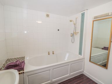 A bathroom with a bathtub shower fixtures and towels on a tiled surface at West Burnbank in Tarset near Bellingham