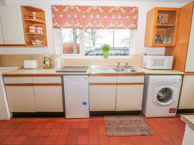 A kitchen with dishwasher washing machine microwave toaster kettle and a window at West Burnbank in Tarset near Bellingham