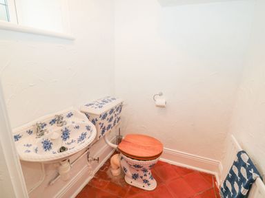 A bathroom with a toilet and sink with blue floral patterns and a wooden toilet seat at West Burnbank in Tarset near Bellingham