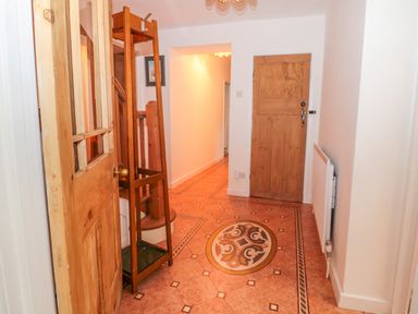 A hallway with patterned tile floor a wooden door a radiator and a wooden coat rack at West Burnbank in Tarset near Bellingham