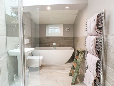 A bathroom with a bathtub sink toilet glass shower and a towel rack with towels at Hen House View in Rugeley