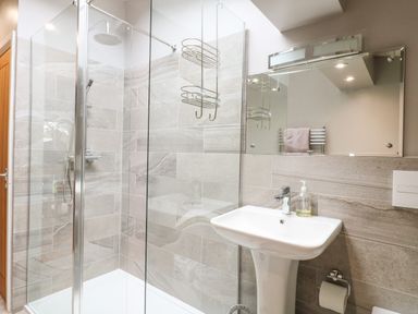 A bathroom with a glass shower enclosure a white sink a mirror and a towel rack at Hen House View in Rugeley