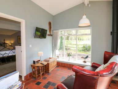 A room with red leather chairs wooden tables and a window with a view at Hen House View in Rugeley