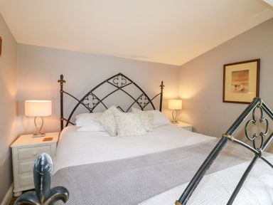 A bedroom with a metal bed frame white bedding floral pillows two bedside tables with lamps and a framed picture on the wall at Hen House View in Rugeley