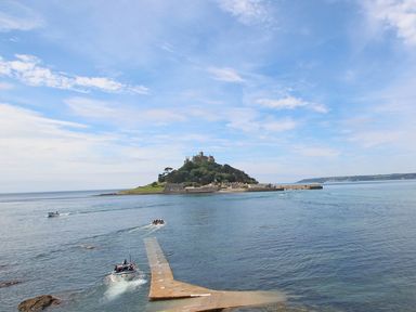 A small island with buildings and a castle surrounded by water with boats near a dock at The Lily Pad in Camborne