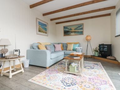 A living room with a light blue sofa and colorful cushions a wooden coffee table and a patterned rug at The Lily Pad in Camborne