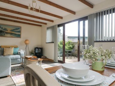 A living room with a sofa a coffee table and a wood burning stove next to large glass doors leading to a patio at The Lily Pad in Camborne