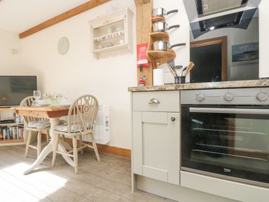 A dining table with two chairs next to a television and an oven in a kitchen at The Lily Pad in Camborne
