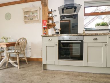 A kitchen with an oven stovetop and dining table with chairs at The Lily Pad in Camborne