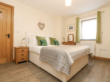 A bedroom with a double bed green curtains and wooden furniture at The Lily Pad in Camborne