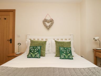 A bedroom with a white bed frame green cushions and wooden furniture at The Lily Pad in Camborne